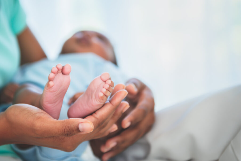 A newborn baby's foot resting gently in the open palm of a mother's hand